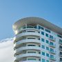 Modern high-rise building with curved facade. Modern architectural designed high-rise building with a curved facade and glass balconies against a clear blue sky.